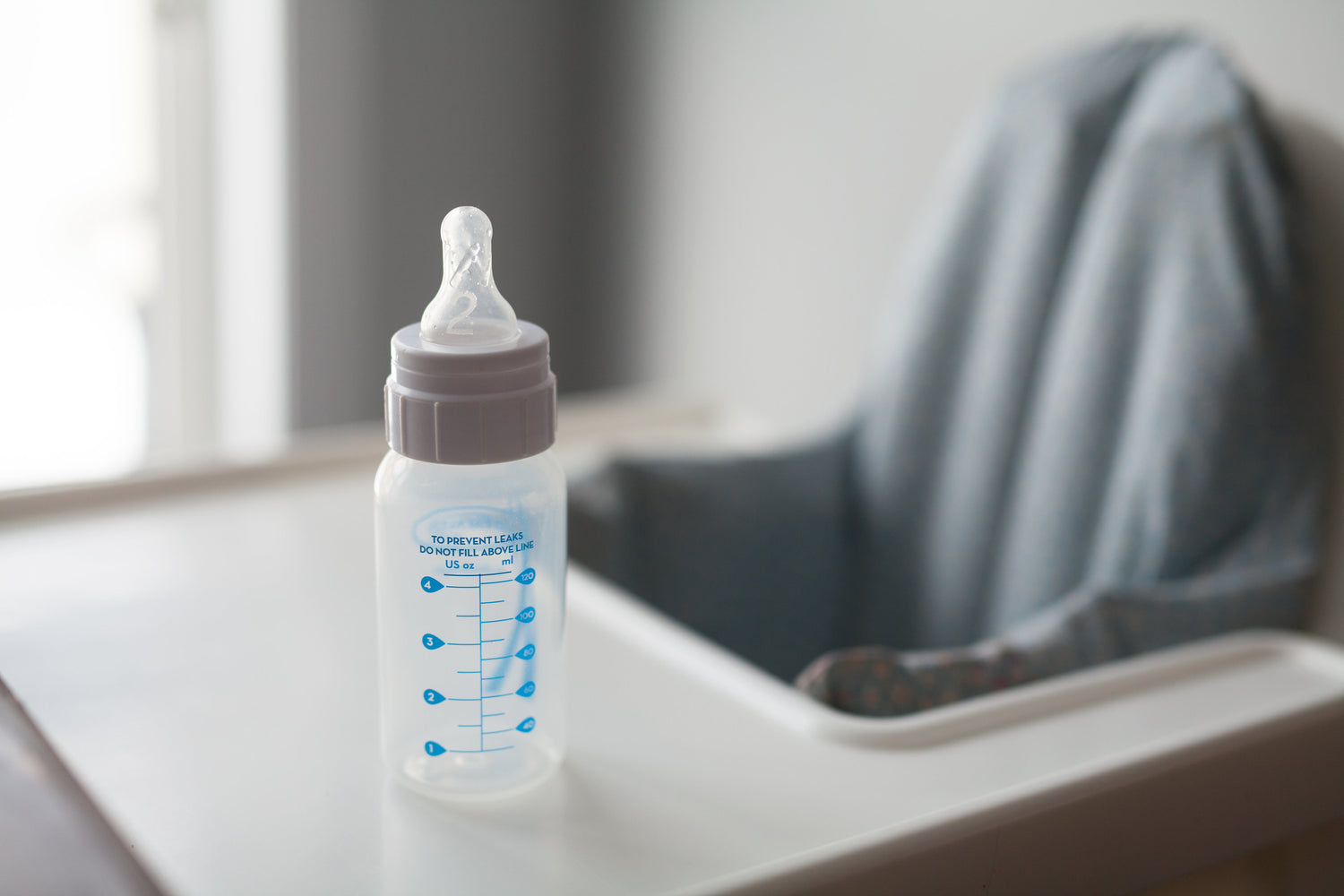 baby bottle on highchair in family room or kitchen with natural fiber cloth around chair